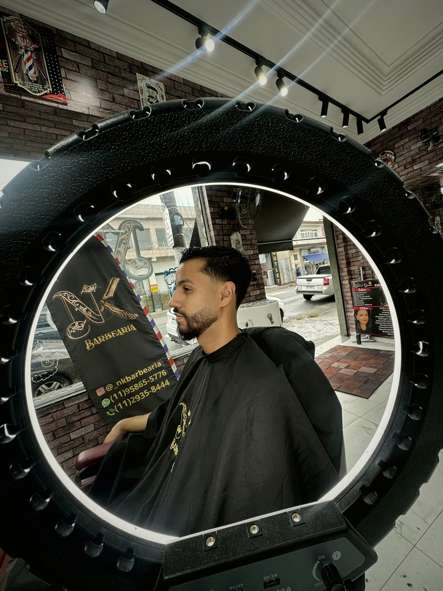 Fachada e interior da NK Barbearia vistos pelo espelho